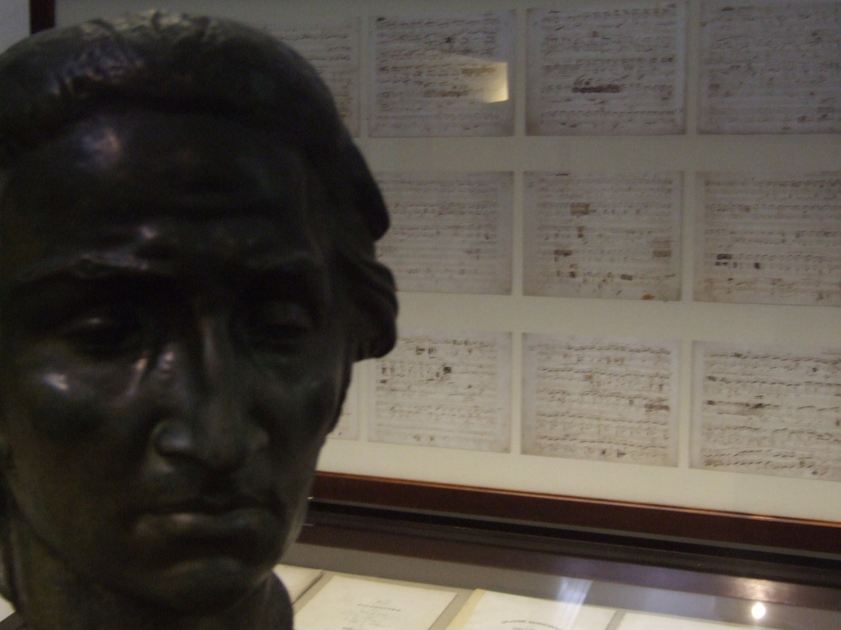 Popiersie Fryderyka Chopina, w tle rękopisy z muzyką mistrza